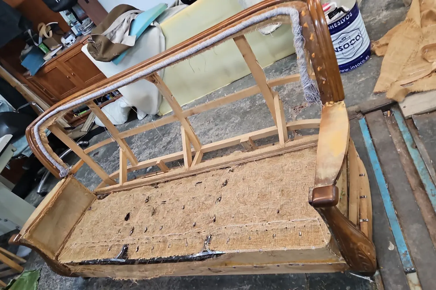 Armazón de un asiento con cinchas y arpillera nuevas durante el proceso de retapizado en el taller